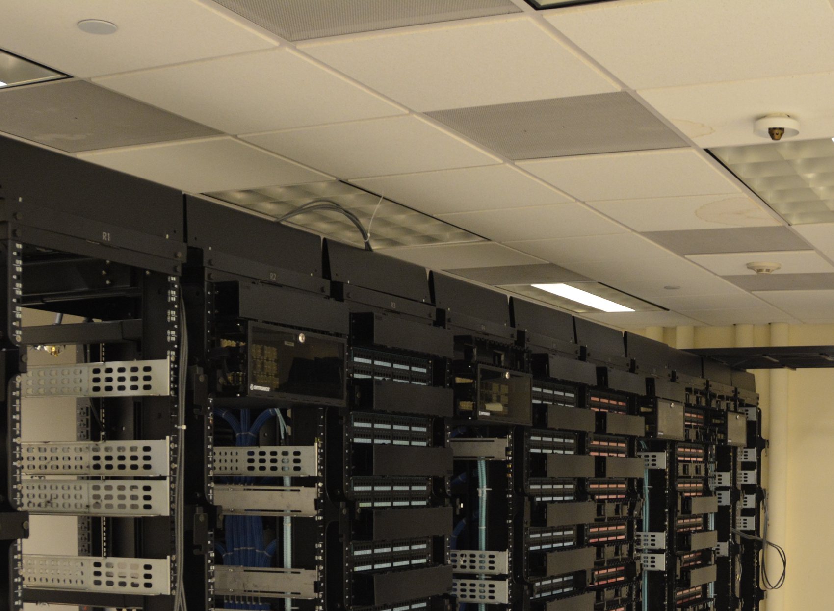 Overhead cable trays above a row of network racks